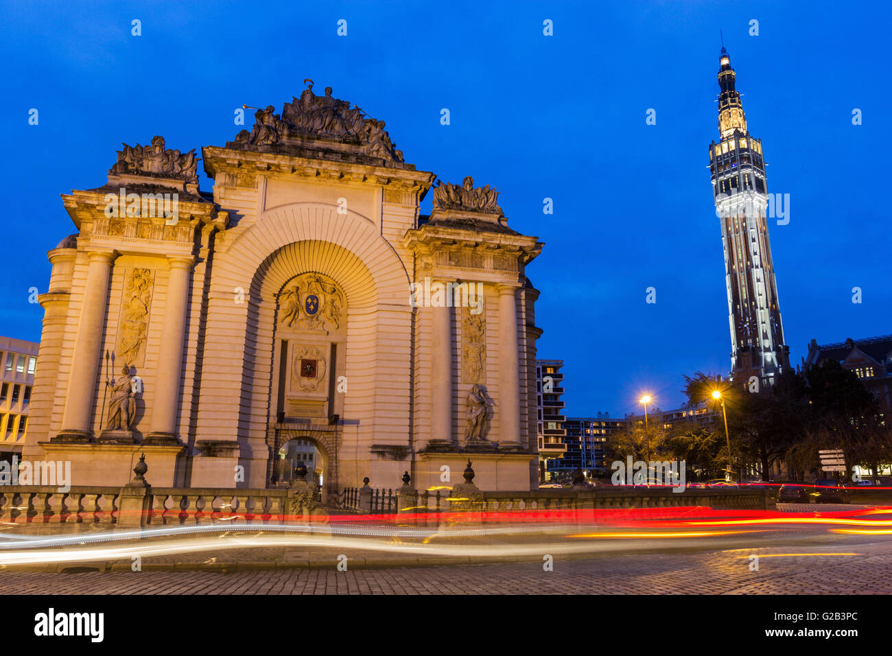 Paris-Tor mit Glockenturm des Rathauses im Hintergrund in Lille in Frankreich am Abend Stockfoto