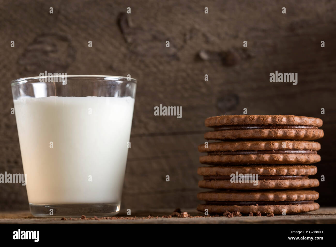 Ein Glas Milch mit Stapel Schokoladenkekse auf alten Holztisch Stockfoto