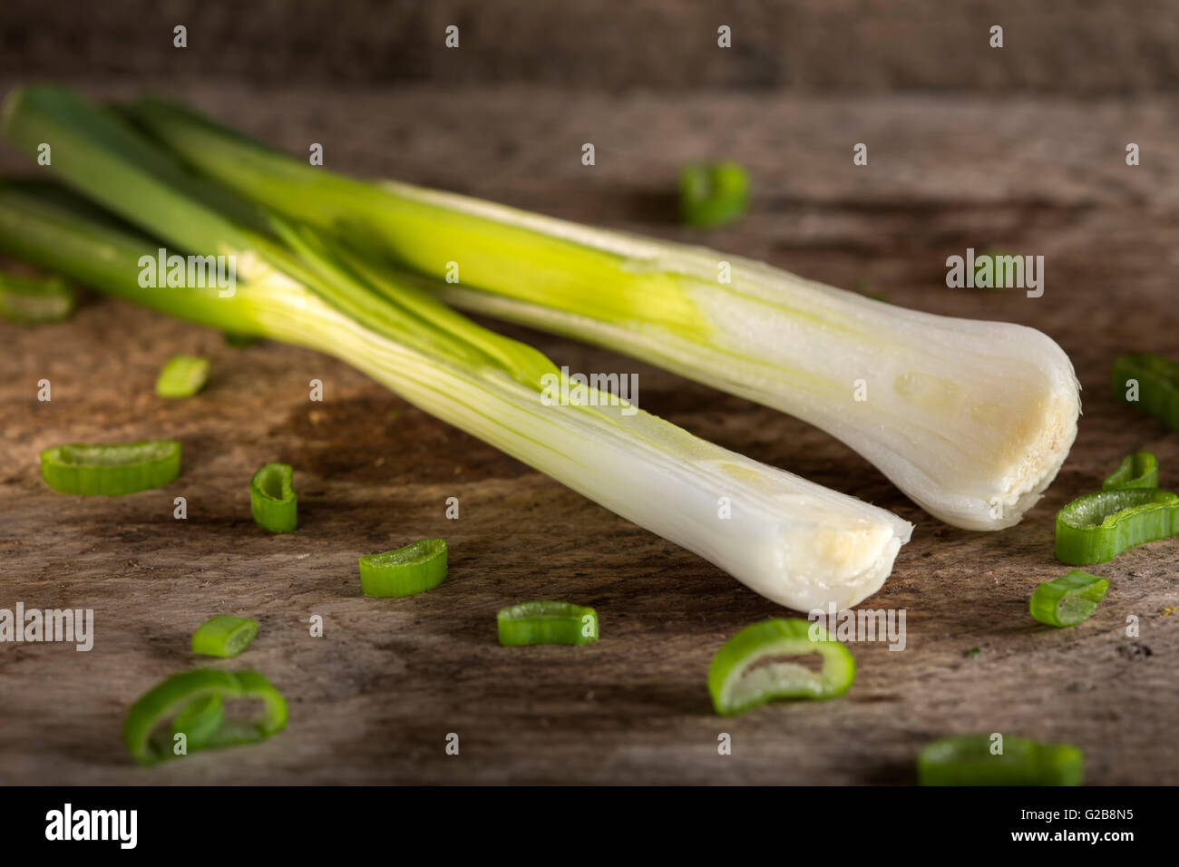 Eine Zwiebel halbieren auch bekannt als Salat Zwiebel, grüne Zwiebel oder Schalotte auf Holz Hintergrund Stockfoto