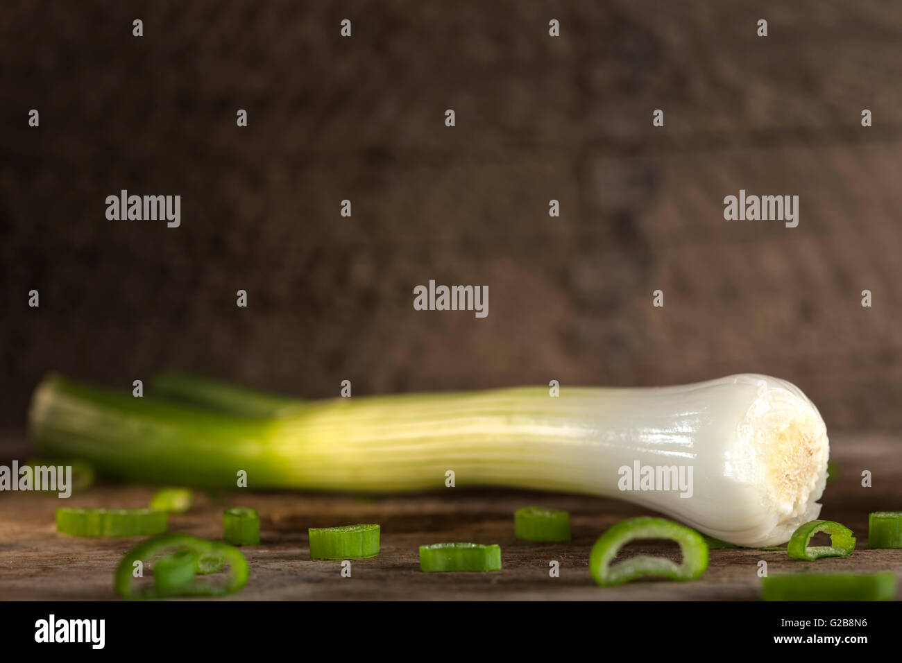 Eine Frühlingszwiebel auch bekannt als Salat Zwiebel, grüne Zwiebel oder Schalotte auf Holz Hintergrund Stockfoto