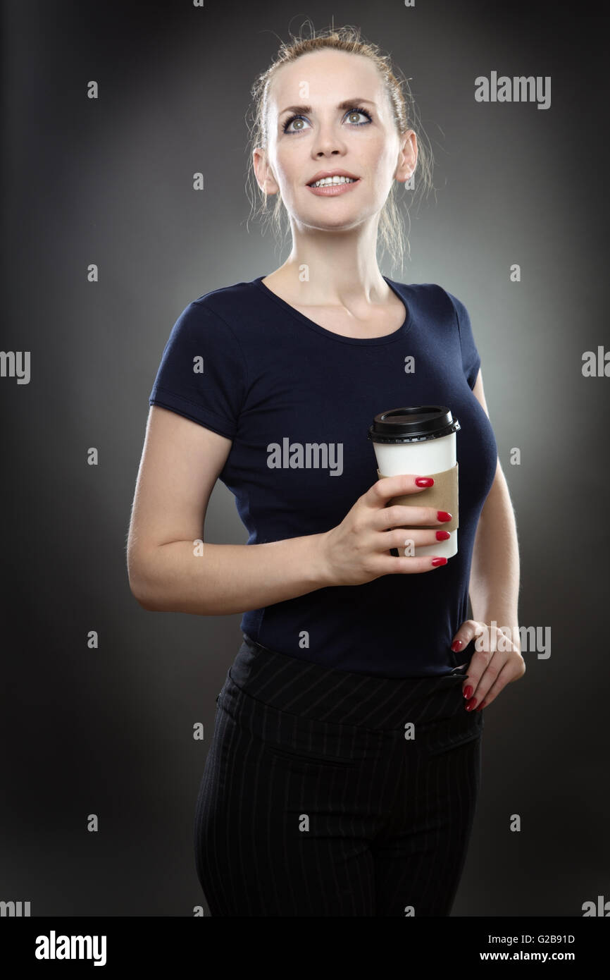 Business Modell stehend, hält einen Imbiss Getränke Tasse.  Gedreht in einem Studio auf einem grauen Hintergrund. Stockfoto