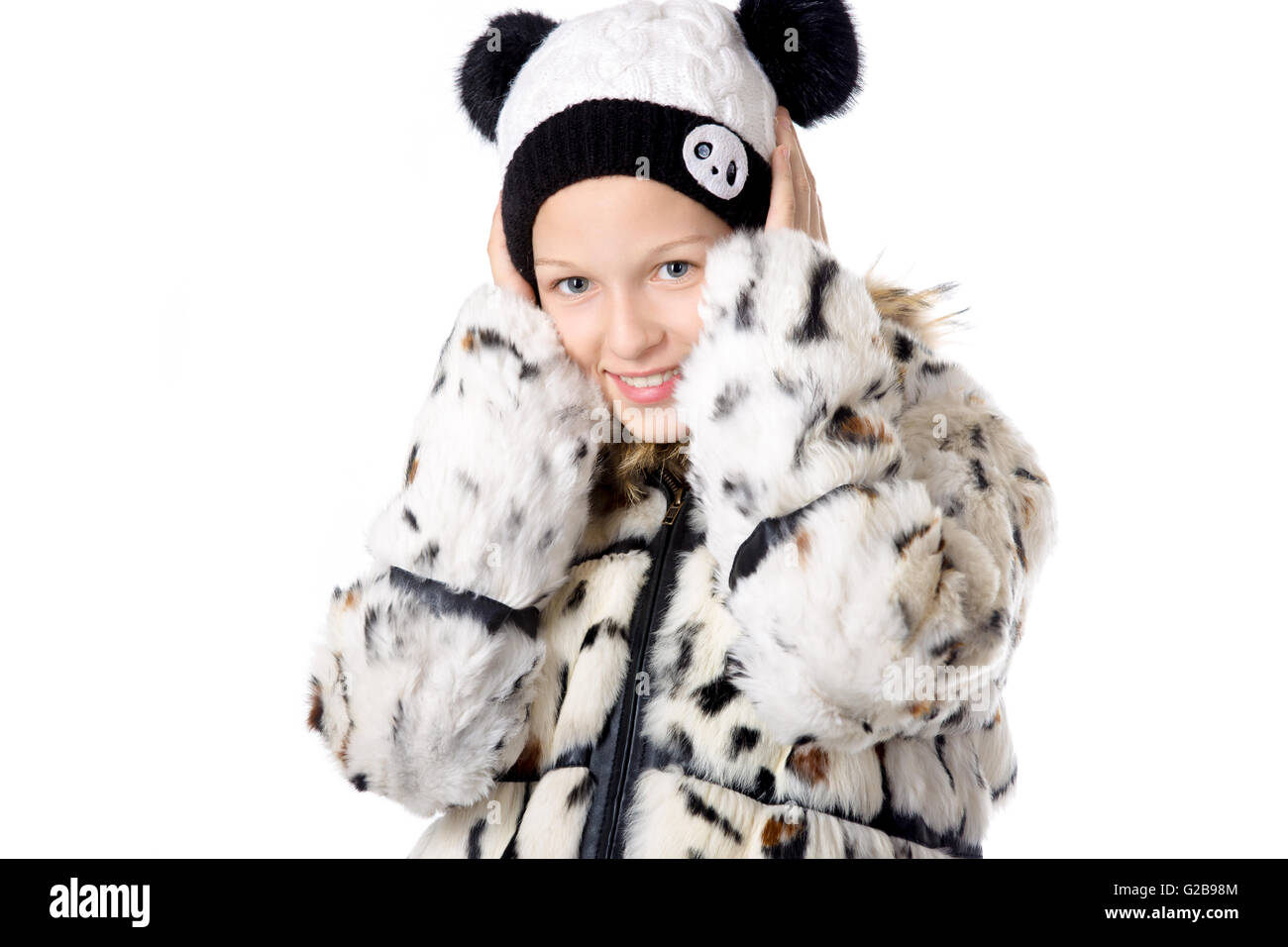 Porträt von lustige schöne lässige kaukasischen Teenager-Mädchen tragen gemütlich weißen Wintermantel und Strickmütze, verstecken ihre Ohren Stockfoto