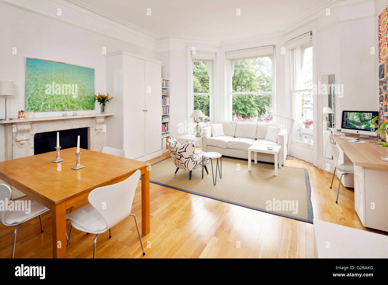 Pembridge Square, Notting Hill. Offene moderne Wohn- und Essbereich. Weiße Möbel mit einem hölzernen Fußböden. Malerei Anove Kamin hängen. Große Fenster. Stockfoto