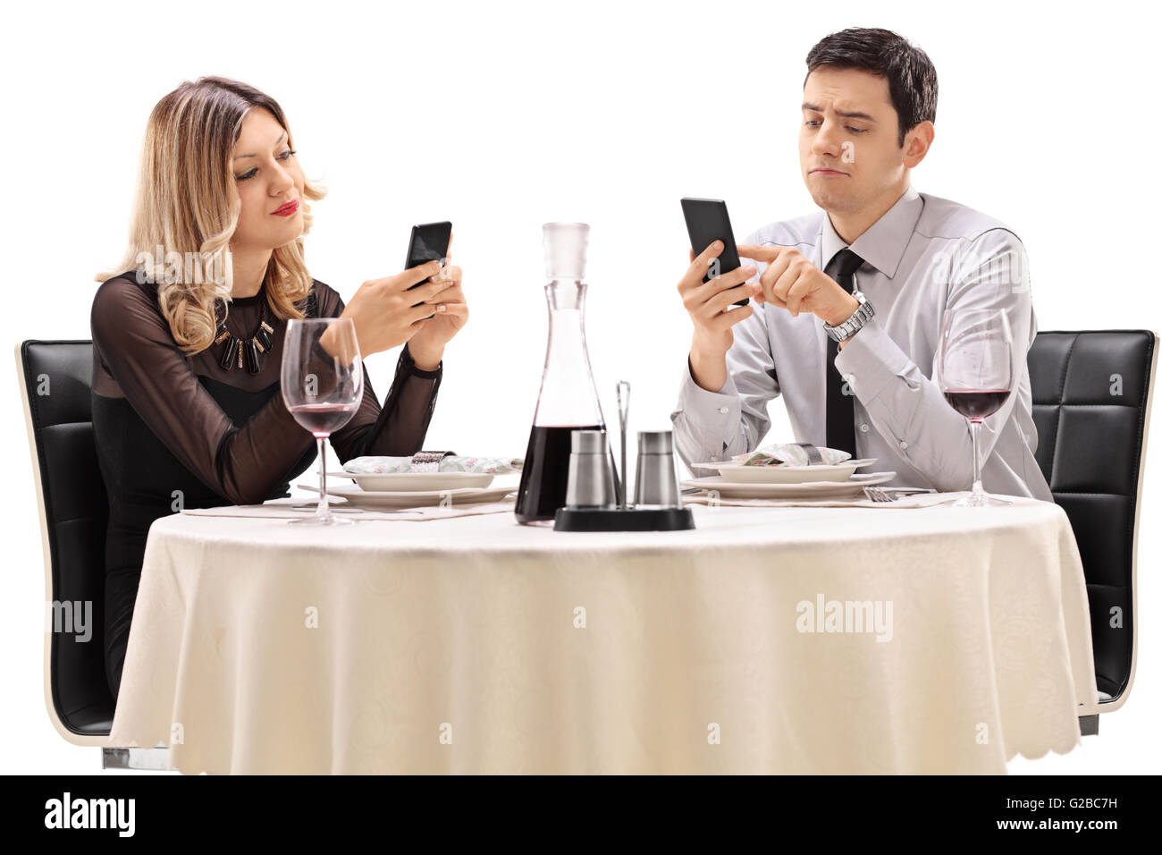 Junger Mann und Frau auf ein Datum mit Blick auf ihre Handys isoliert auf weißem Hintergrund Stockfoto