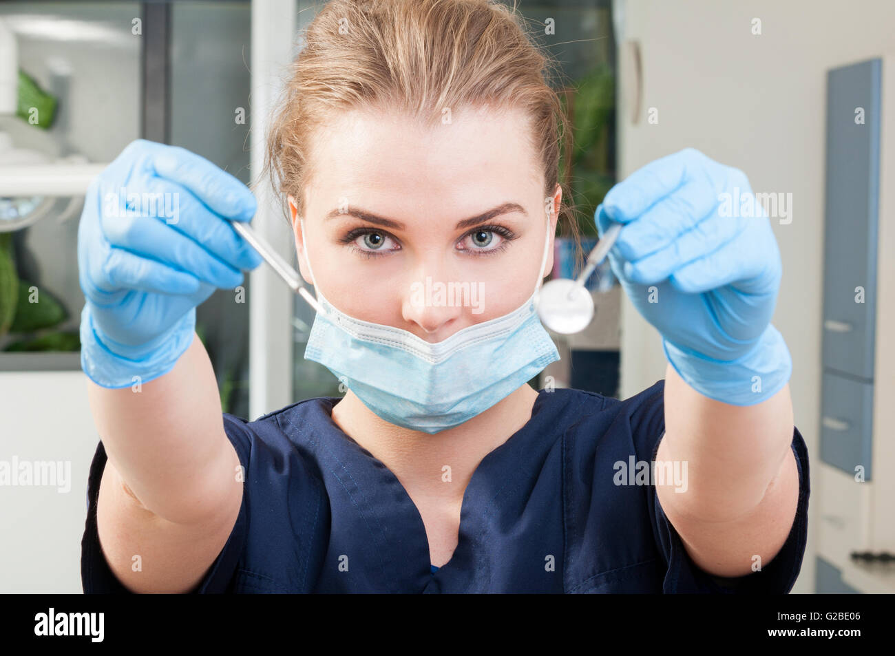 Attraktive Frau Zahnarzt Maske und blaue Handschuhe trägt und hält  zahnärztliche Instrumente in ihrer ausgestreckten Armen immer bereit für  eine consult Stockfotografie - Alamy