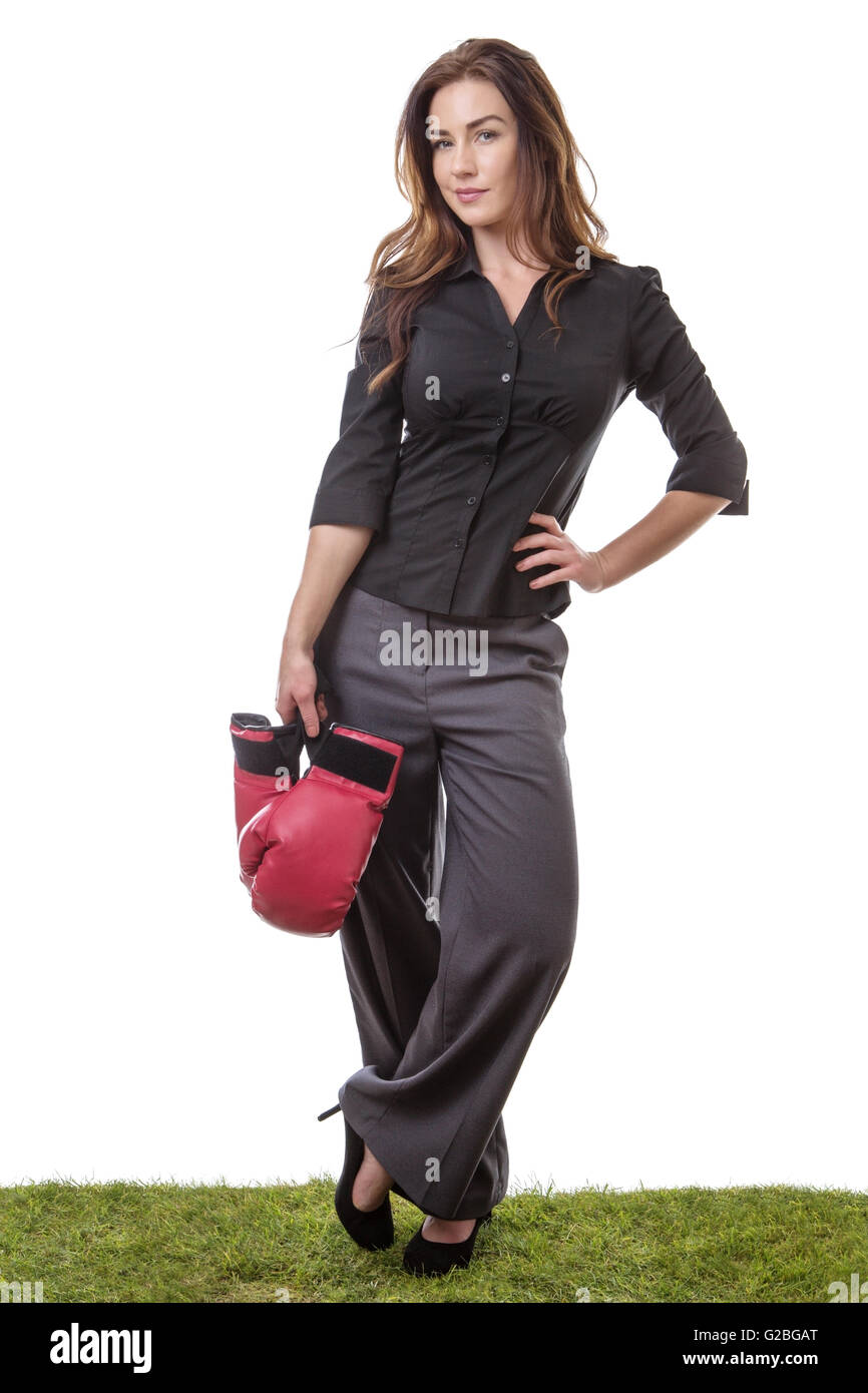 SLim-Modell einen Business-Anzug tragen, einige Boxhandschuhe in einer Hand hält, auf dem Rasen stehen. Stockfoto