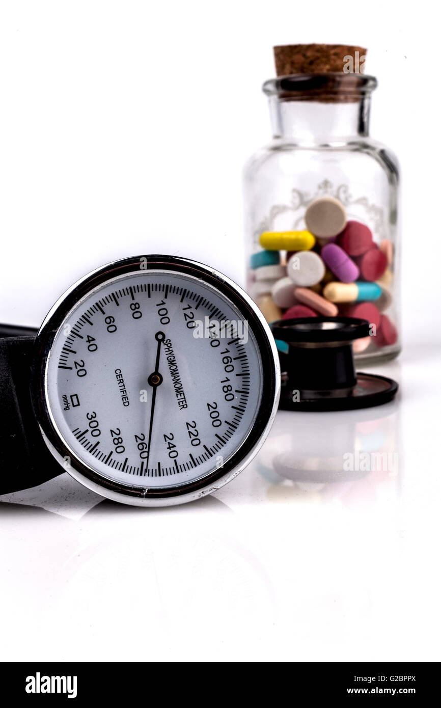 Farbigen Pillen in ein Gefäß mit Blutdruckmessgerät und Stethoskop schwarz Stockfoto