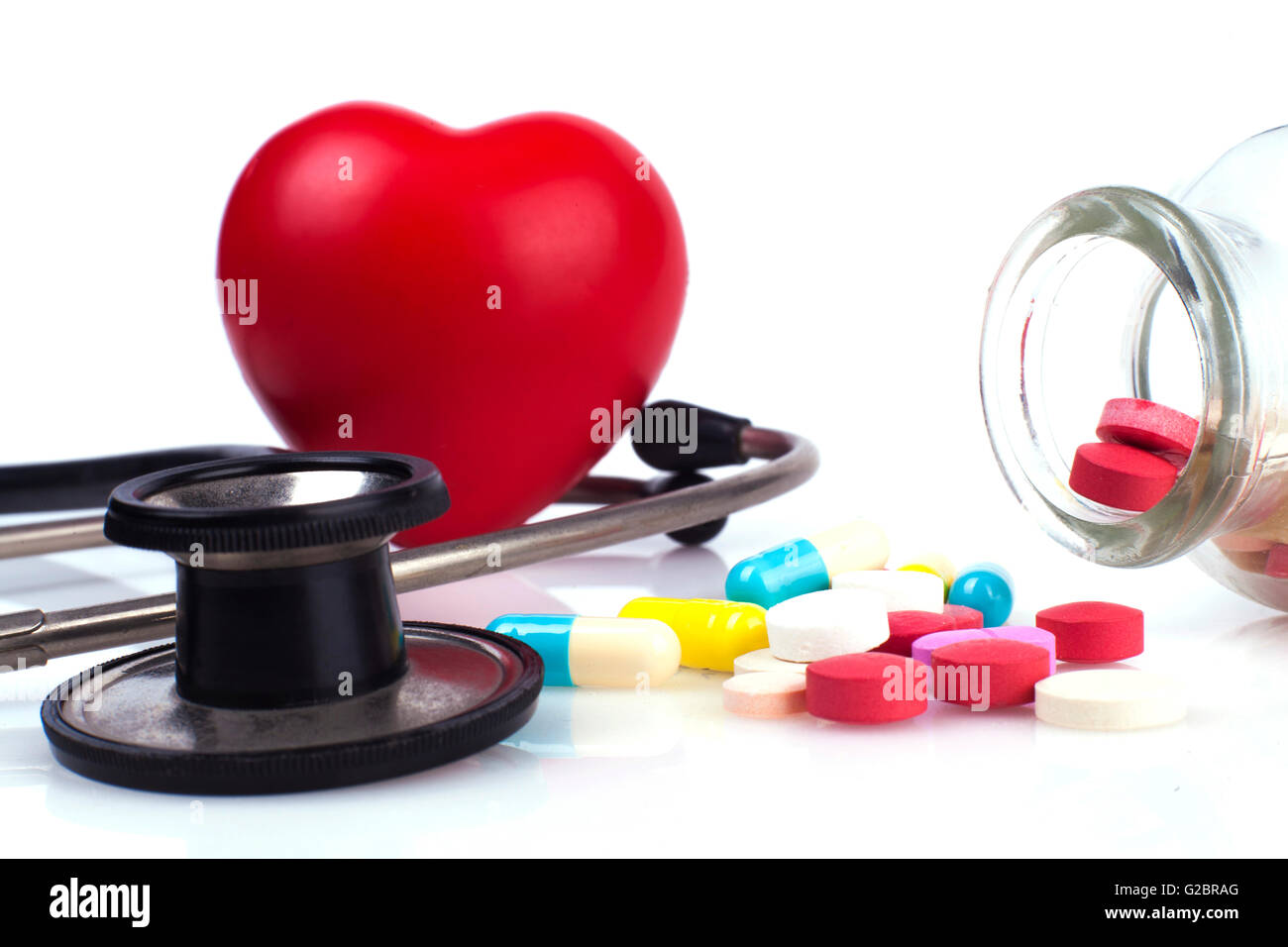 Farbigen Pillen in ein Gefäß mit Blutdruckmessgerät und Stethoskop schwarz Stockfoto