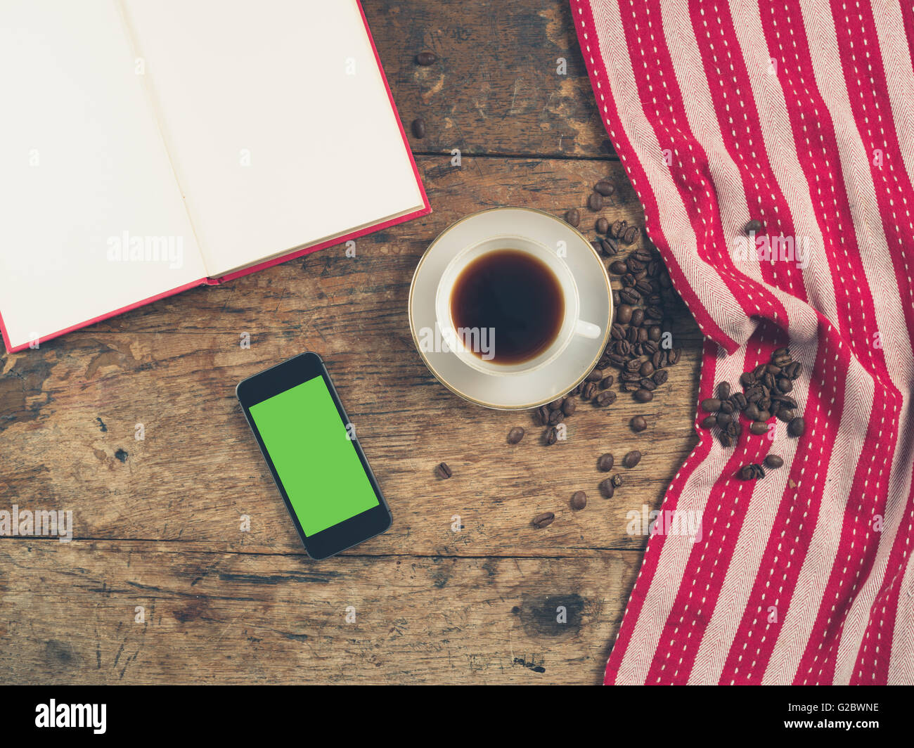 Overhead Schuss von Kaffee-Konzept mit Tasse, Geschirrtuch, ein offenes Buch und ein Smartphone mit einem green-screen Stockfoto