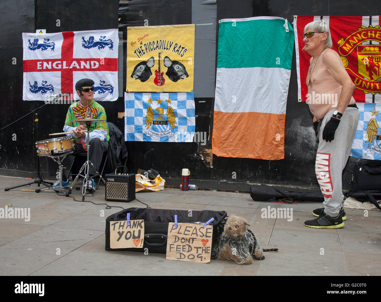 The Piccadilly Rats Mancunian Busking Band und Straßentheater-Performance. Alberne Bandleute, einzigartige, kratzige Rock'n'Roll-Straßenaufführungen, die Instrumente für Geld spielen: Bettler, Tänzer, Straßenunterhalter und Straßenmusiker mit Hund in Piccadilly Manchester, Großbritannien Stockfoto