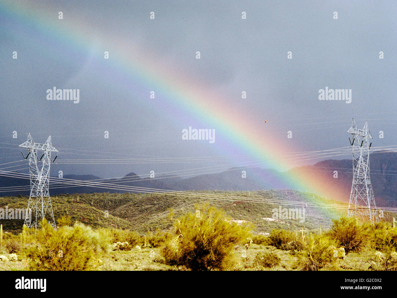 Hochspannungsleitungen und Türme mit einem lebendigen, dramatische Regenbogen in der Wüste nördlich von Phoenix, Arizona, USA Stockfoto