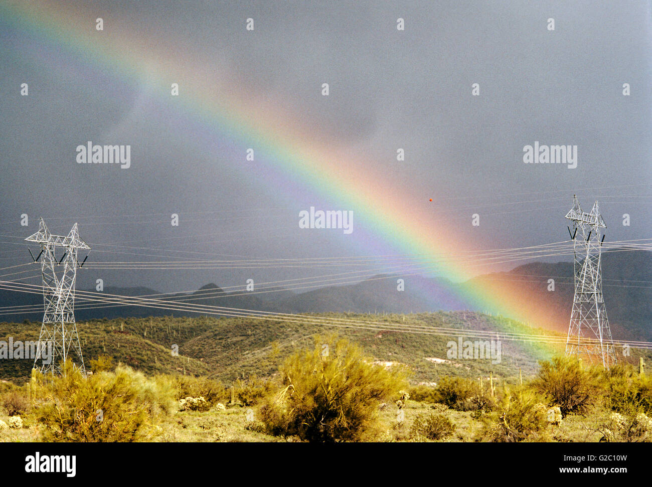 Hochspannungsleitungen und Türme mit einem lebendigen, dramatische Regenbogen in der Wüste nördlich von Phoenix, Arizona, USA Stockfoto