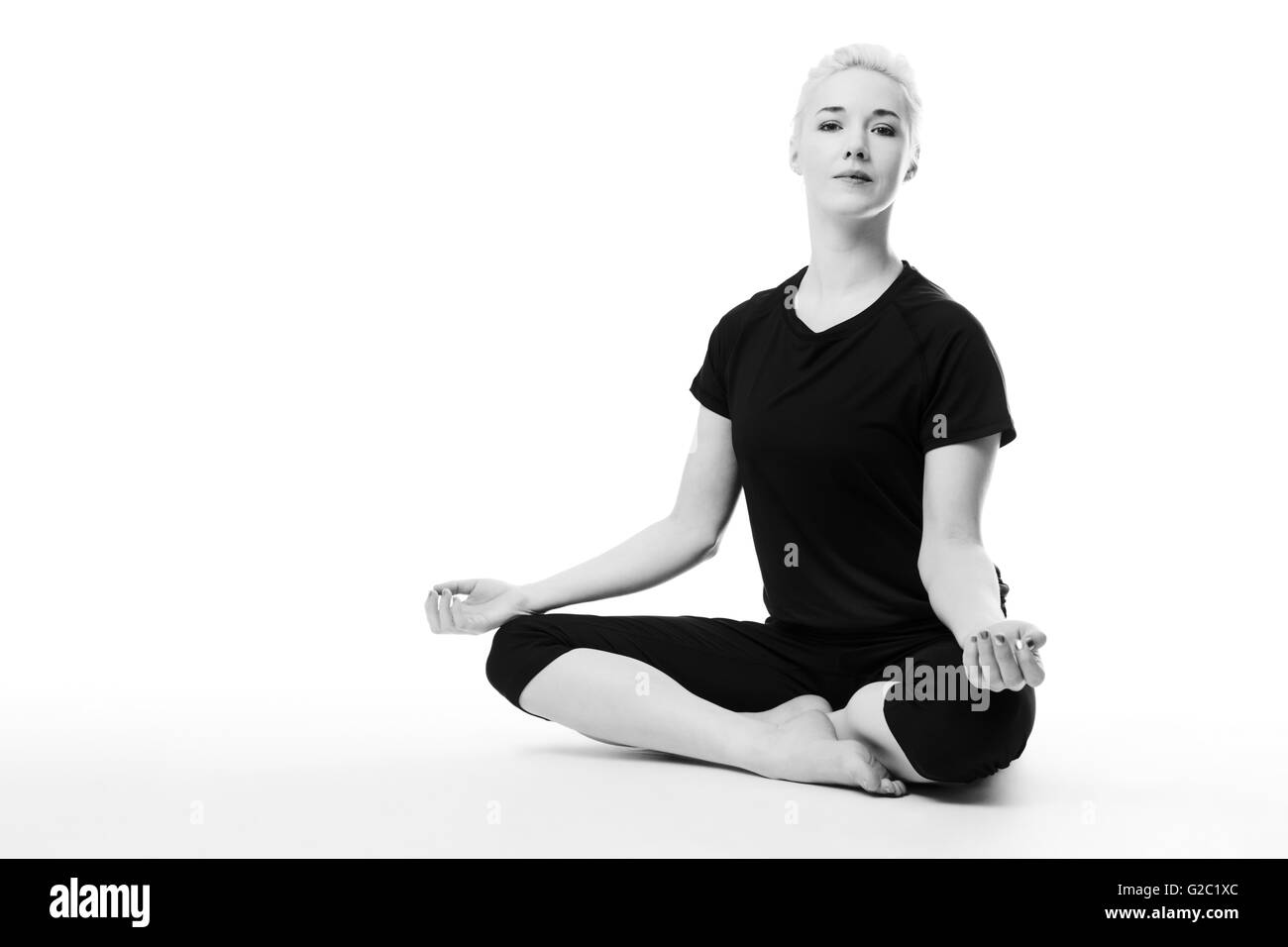 Yoga-Frau Schneidersitz auf dem Boden sitzend Stockfoto