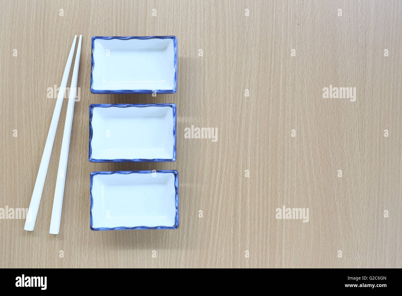 Weiße Stäbchen und Schüssel in der Draufsicht auf Holz Hintergrund für Design-Konzept Essen. Stockfoto