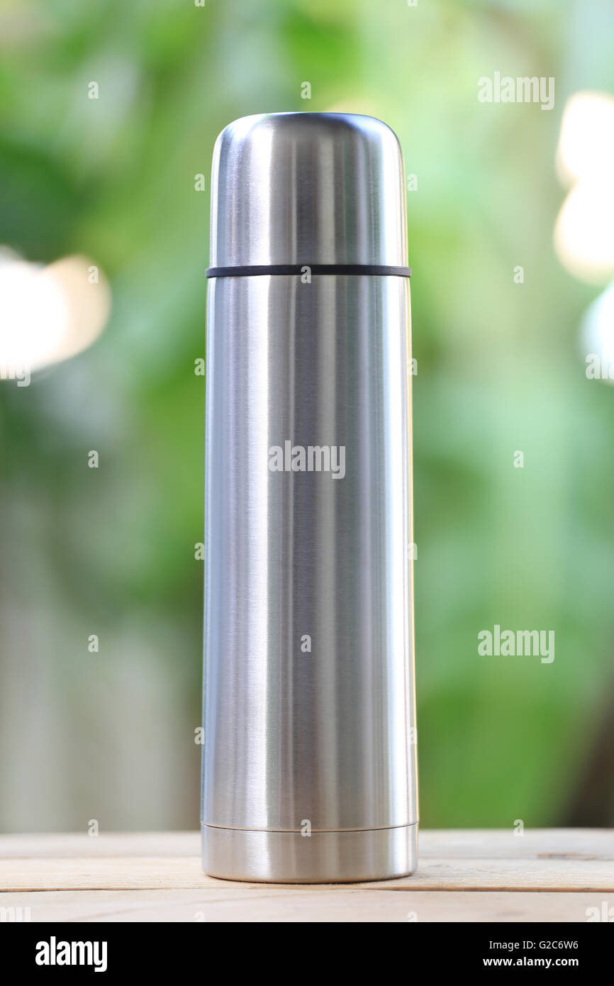 Wasser Glas Aluminium (Aluminium-Becher) auf Holzboden und haben grüne Farbe Natur im Hintergrund. Stockfoto