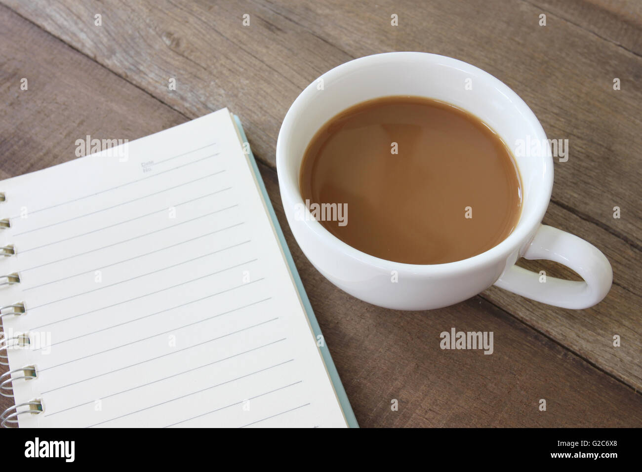 Weiße Kaffeetasse und leeres Buch auf einen Holzboden und Konzept für Getränke. Stockfoto