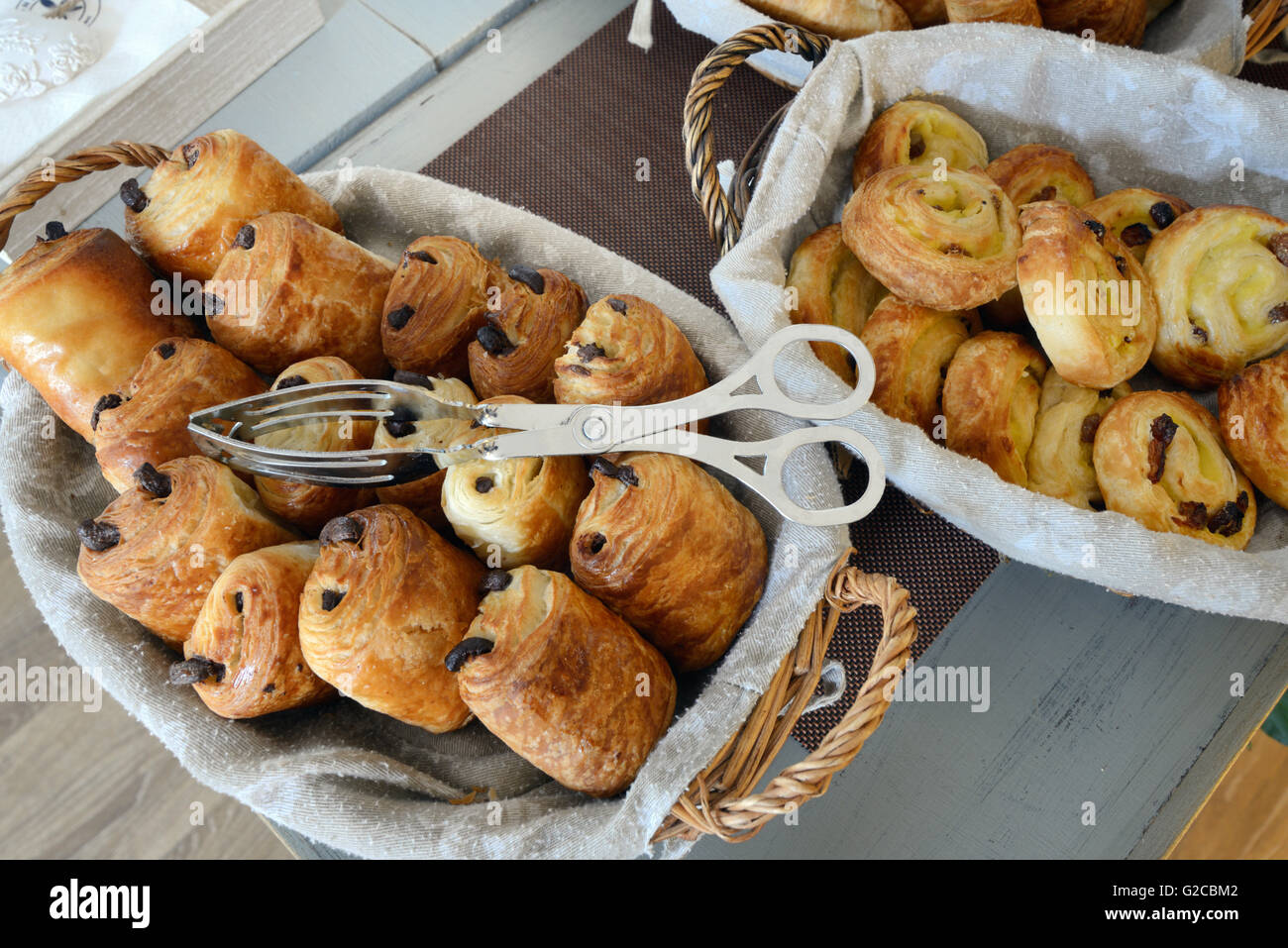 Anzeige von Französisch Gebäck einschließlich Pain au Chocolat oder Schokolade Rollen und Schmerzen au Rosinen oder Johannisbeere Brötchen in Brotkörbe Stockfoto