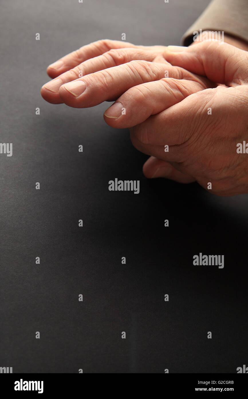 Ein Mann packt seine schmerzenden Hand auf einem dunklen Hintergrund mit Textfreiraum. Stockfoto