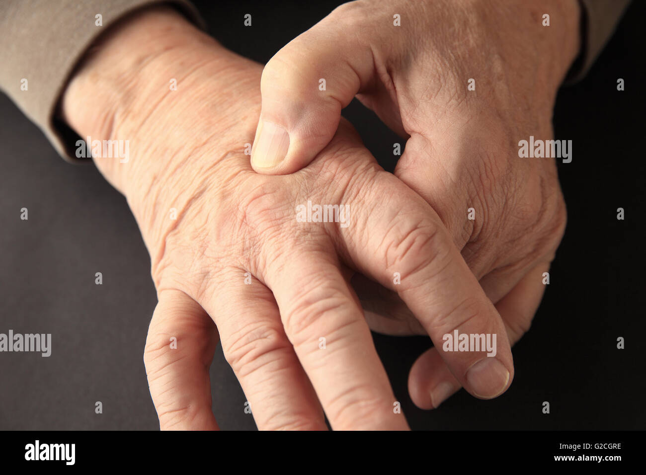 Senior woman zeigt an, wo er auf der Rückseite seiner Hand Schmerzen verspürt. Stockfoto