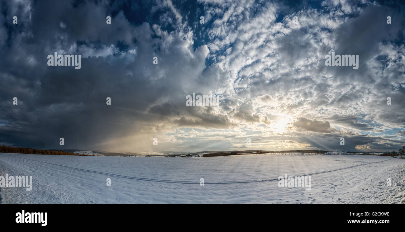 Ein Panorama eines Sonnenuntergangs im Winter mit Wolken und Sonnenstrahlen, die Hoffnung gibt. Stockfoto