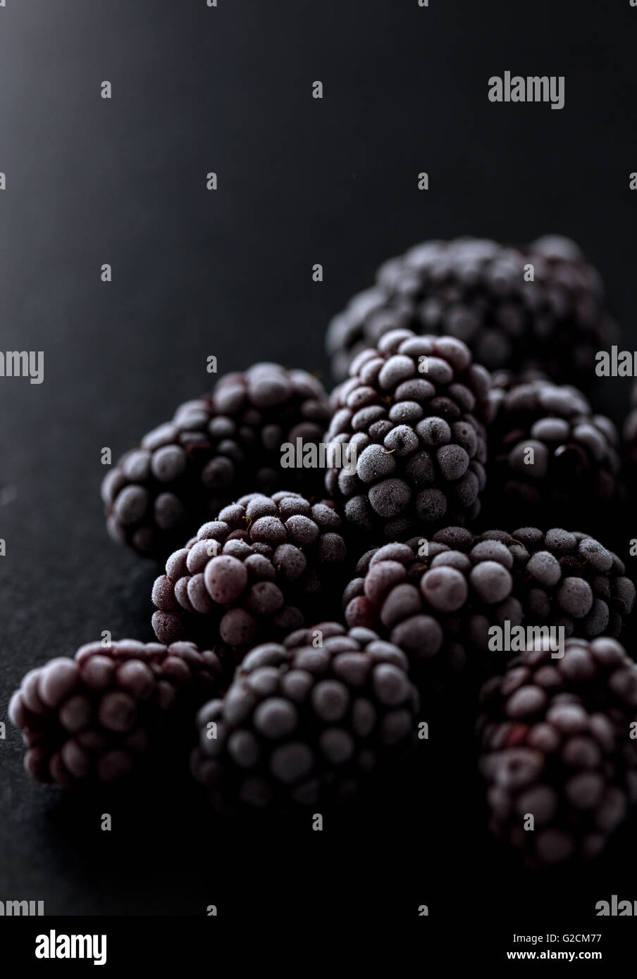 Brombeeren eingefroren auf einem schwarzen Stein, Makro-Foto zeigt eine schöne Textur Stockfoto