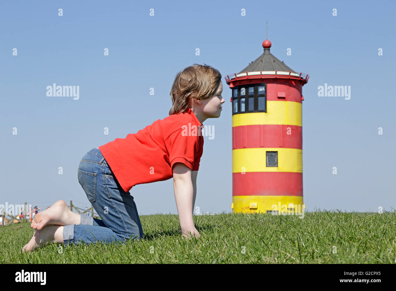 kleiner Junge vorgibt, schauen Sie in das Fenster des Pilsum Leuchtturm, Pilsum, Ostfriesland, Niedersachsen, Deutschland Stockfoto