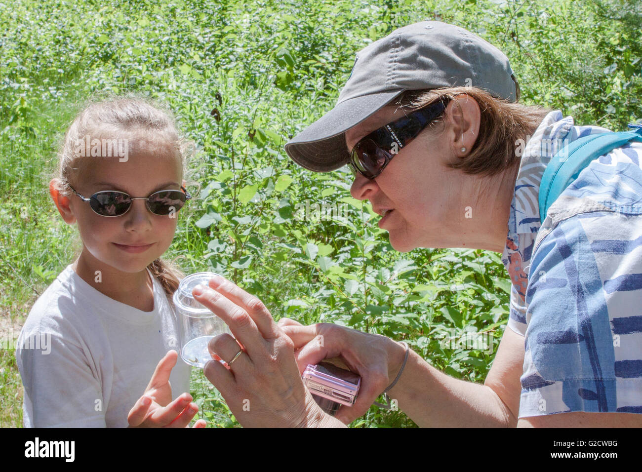 Lehrer der ersten Klasse und Schüler untersuchen ein Insekt in das Glas Stockfoto