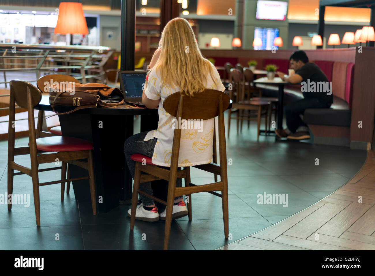 Blonde Frau, die Arbeiten am Laptop im stilvollen Restaurant des Flughafens Stockfoto