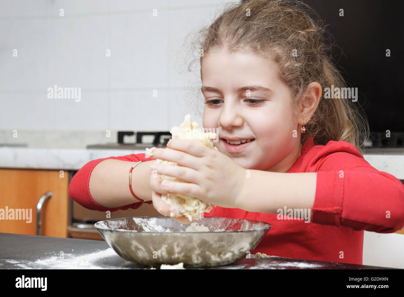 glückliches Mädchen Kneten von Teig mit den Händen in der Küche Stockfoto