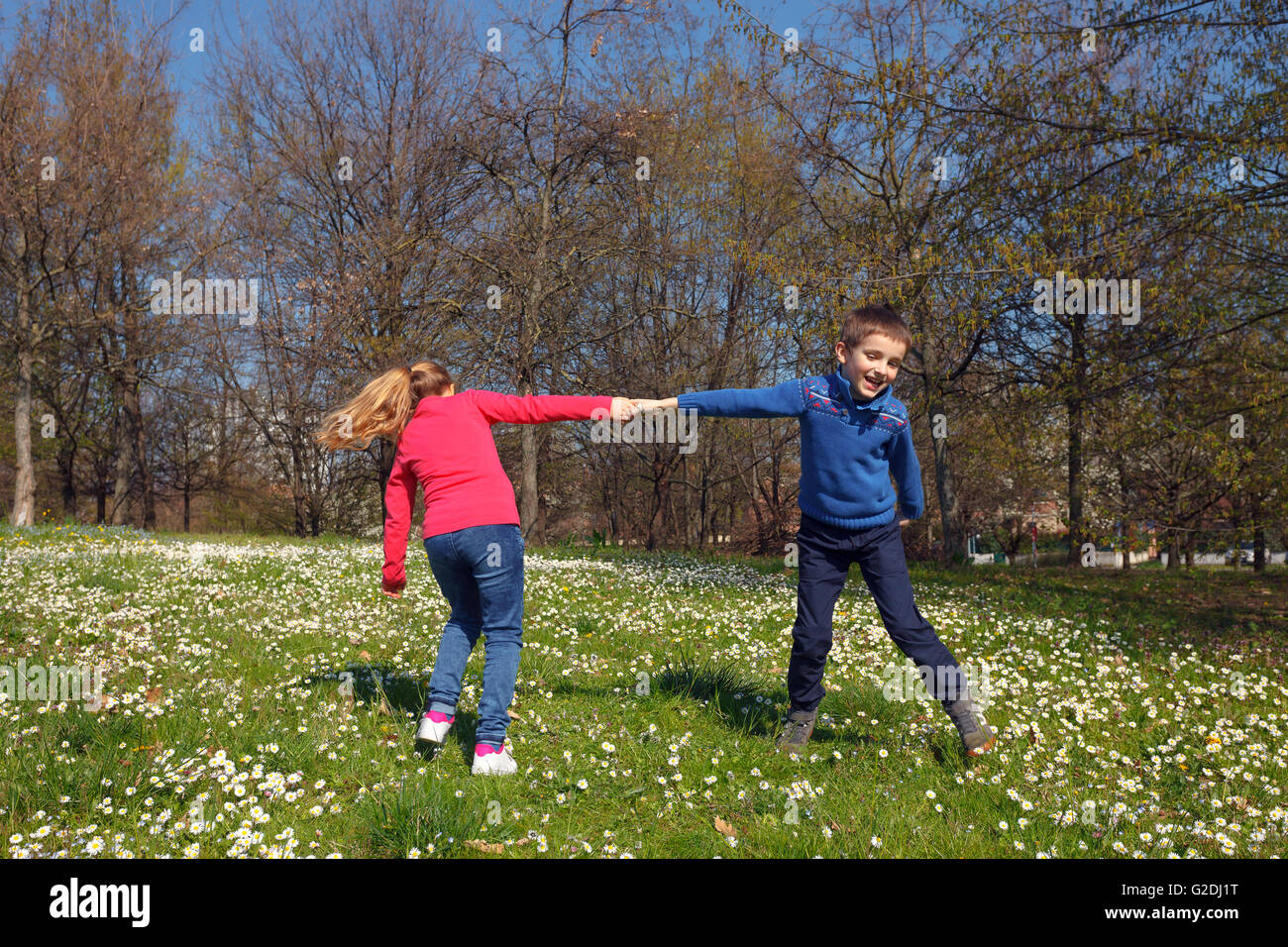 glückliche Kinder Hand hält und auf dem Rasen spielen Stockfoto