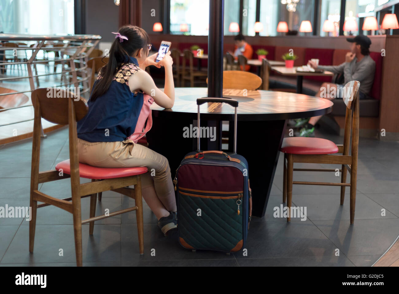 Junge asiatische Frau, die an ihr Mobiltelefon im stilvollen restaurant Stockfoto