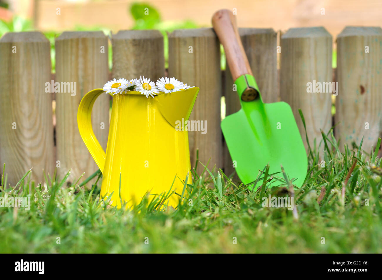 bunte kleine Schaufel und kann gegen einen hölzernen Rahmen im Garten Stockfoto