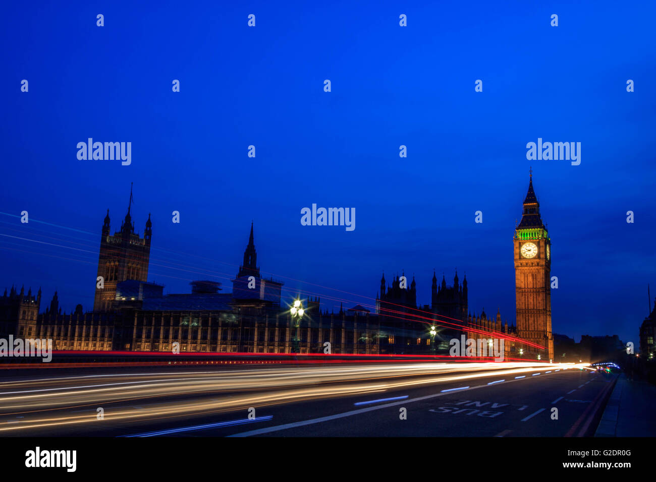 Palast von Westminster in London und dem Big Ben in der Nacht mit Fahrzeug hinterließ eine Schneise entlang der Straße, mit einem klaren blauen Himmel. Stockfoto