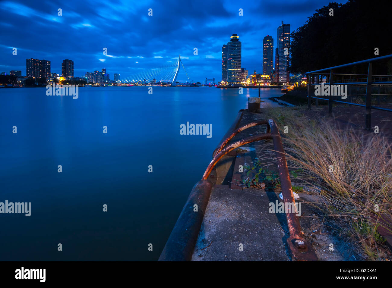 Skyline von Rotterdam während der blauen Stunde in der Abenddämmerung. Langzeitbelichtung macht die Bewegung der Wolken am Himmel sichtbar. Stockfoto