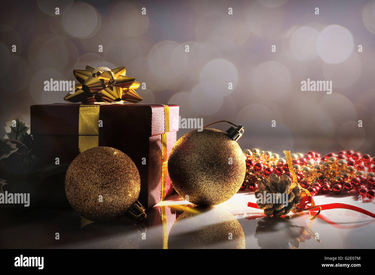 Düsternis Weihnachtsdekoration auf einer weißen Tafel Methacrylat. Mit roten Geschenkbox mit Goldband, zwei Goldene Kugeln und Perlen. Vorne Stockfoto