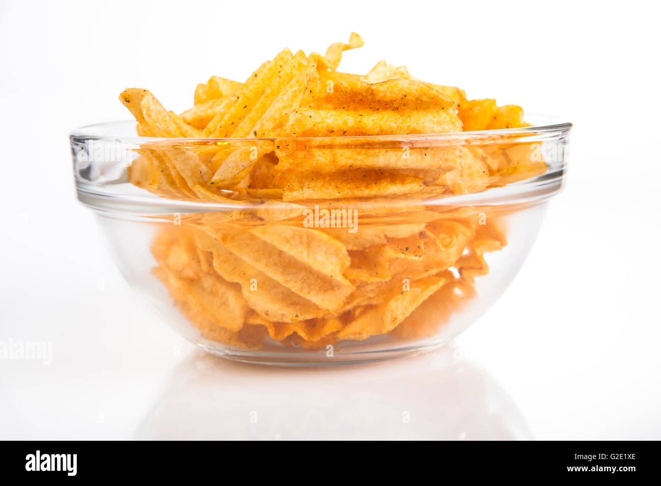 Glasschüssel voll mit goldenen würzige Potatoe Chips auf weißem Hintergrund Stockfoto