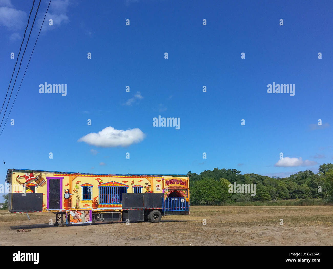 Karneval-Anhänger in einem leeren Grundstück mit Bäumen im Hintergrund und ein strahlend blauer Himmel Stockfoto