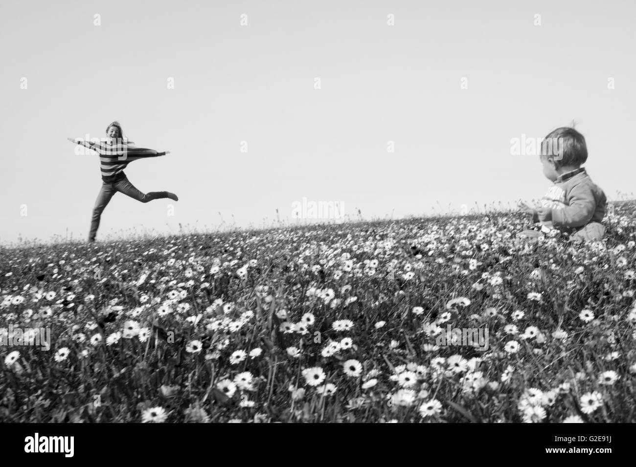 Frau im Bereich der Wildblumen mit Baby-Sitter im Vordergrund springen Stockfoto