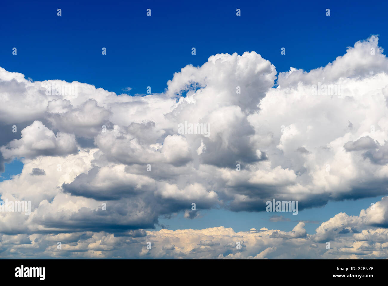 Weiße Cumulus-Wolken und graue Wolken am blauen Himmel Stockfoto