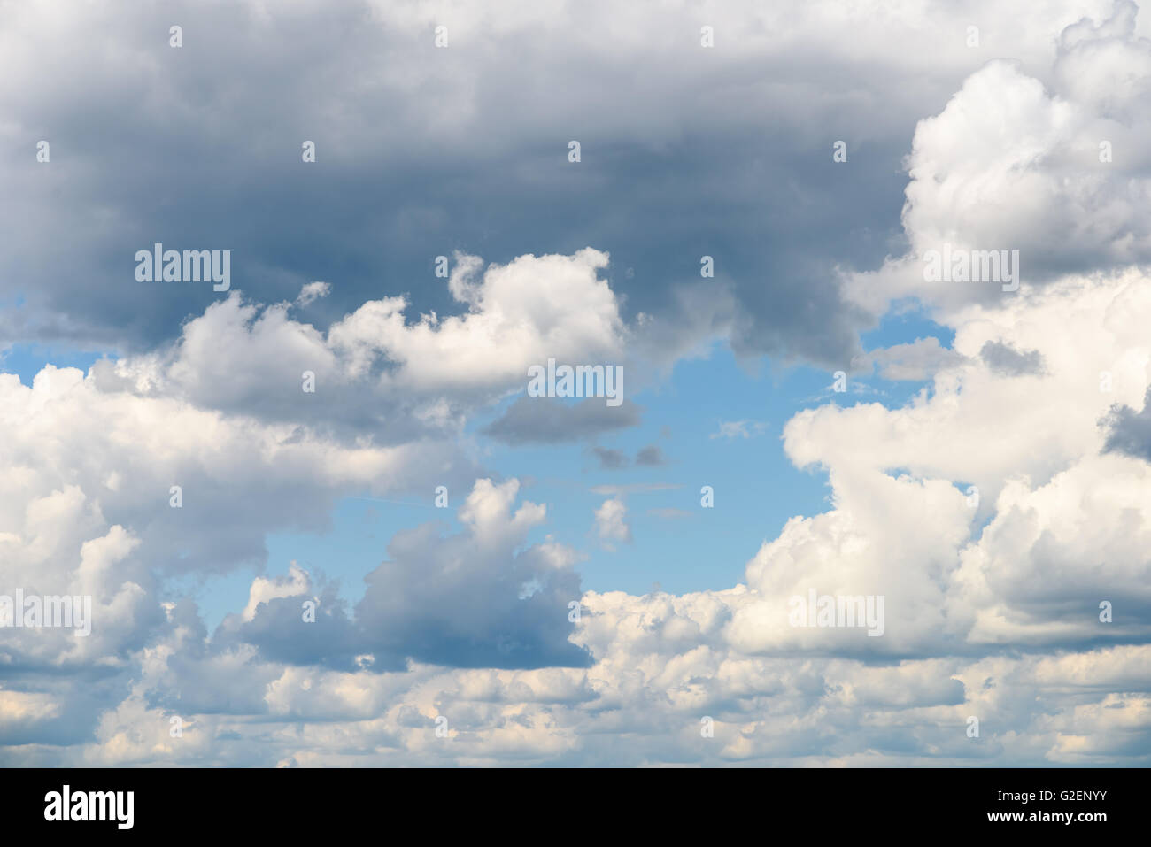 Weiße Cumulus-Wolken und graue Wolken am blauen Himmel Stockfoto
