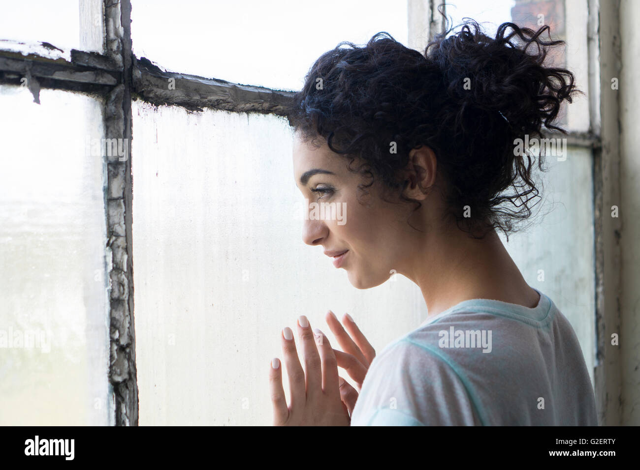 Glückliche junge Frau aus dem Fenster Stockfoto