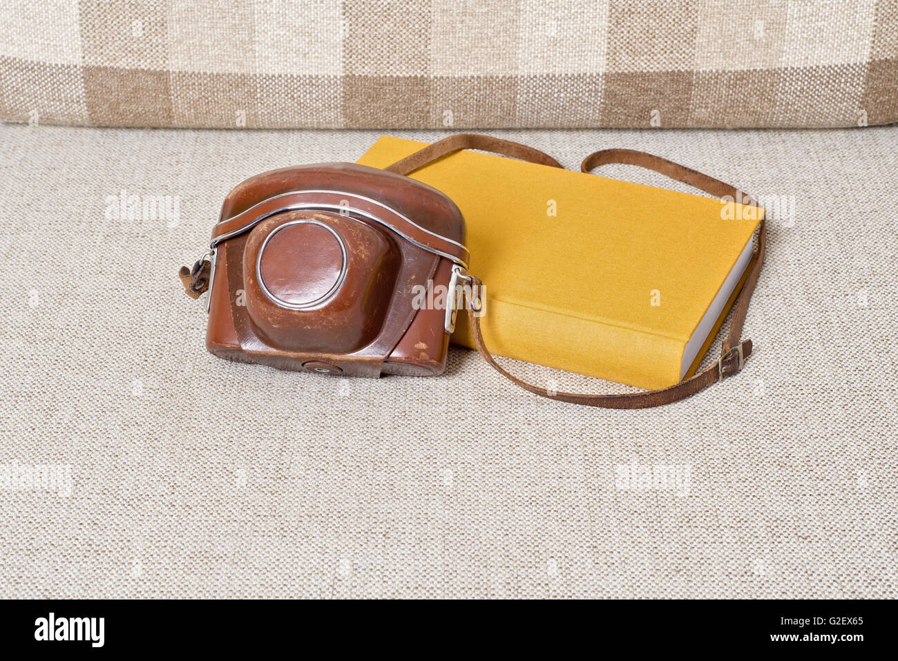 alte Vintage-Kamera und gelbe Buch auf dem sofa Stockfoto