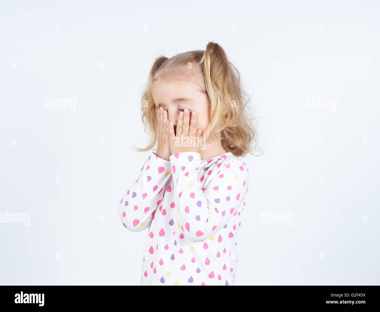 Kleine Mädchen weinen, bedeckte sein Gesicht mit den Händen. Stockfoto