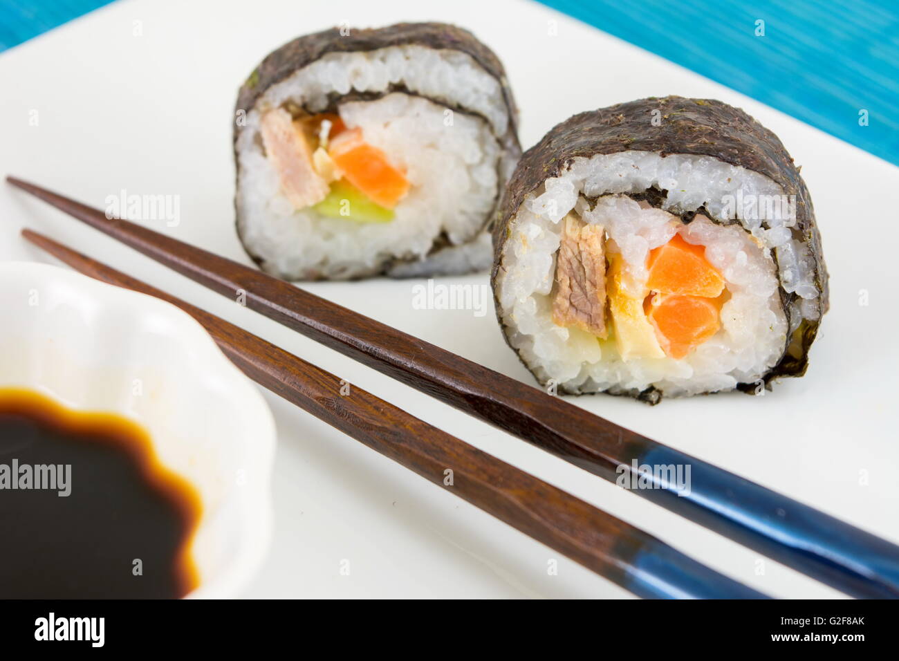 Sushi-Rollen mit hölzernen Stäbchen serviert Stockfoto