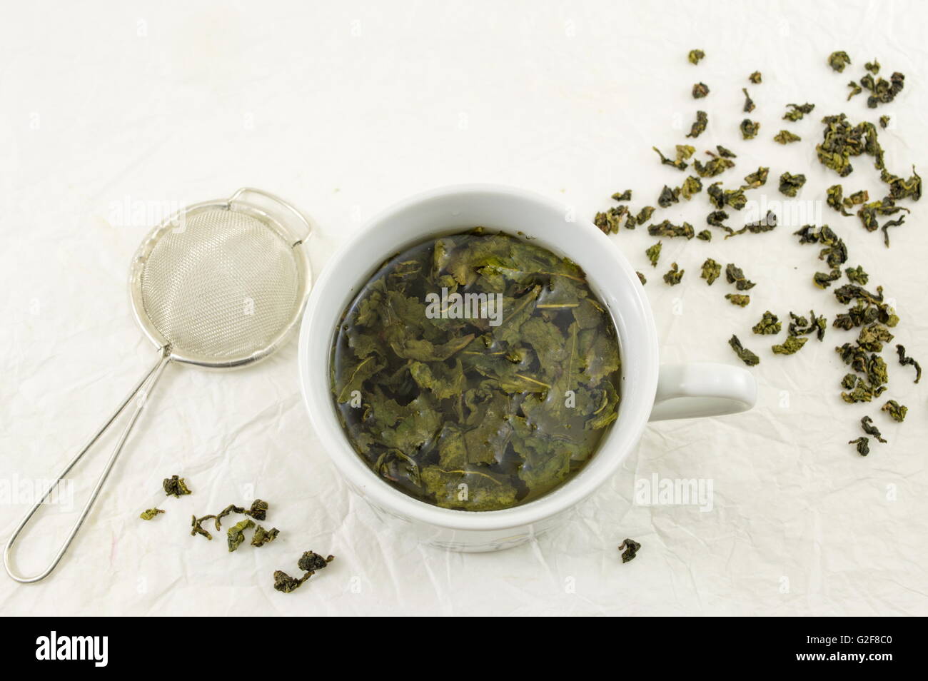 Grüner Tee mit Jasmin Blatt in eine Tasse auf Seidenstoff Stockfoto