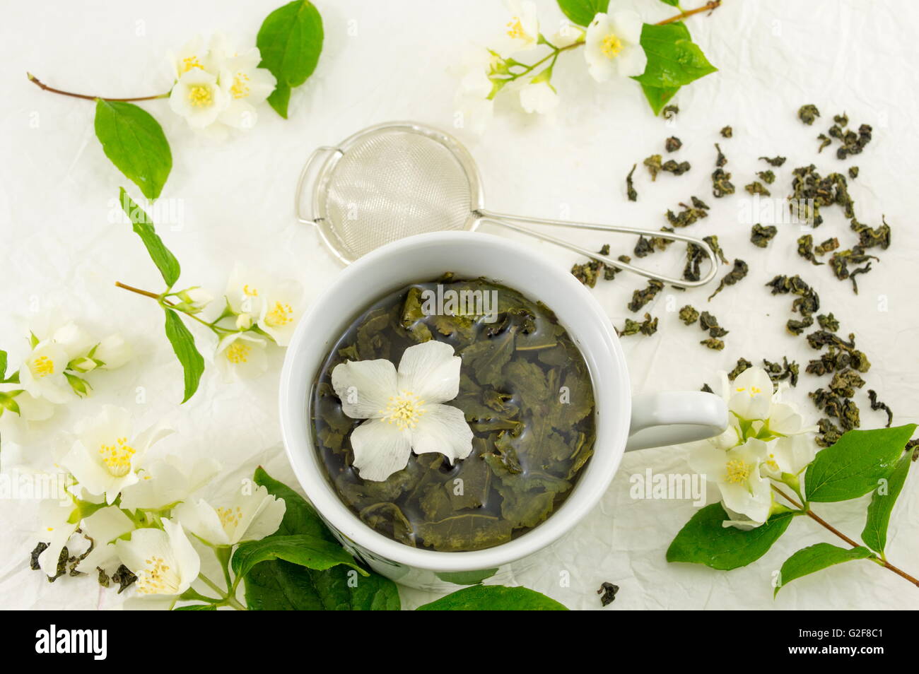 Grüner Tee mit Jasmin Blatt in eine Tasse auf Seidenstoff Stockfoto