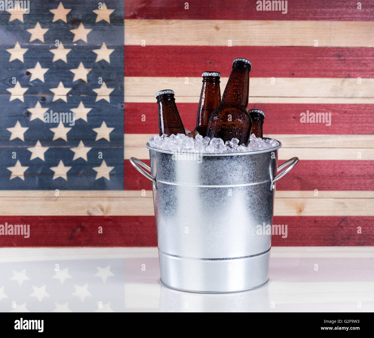Einen Eimer kaltes Flaschenbier auf Eis mit hölzernen USA-Flagge im Hintergrund. Stockfoto