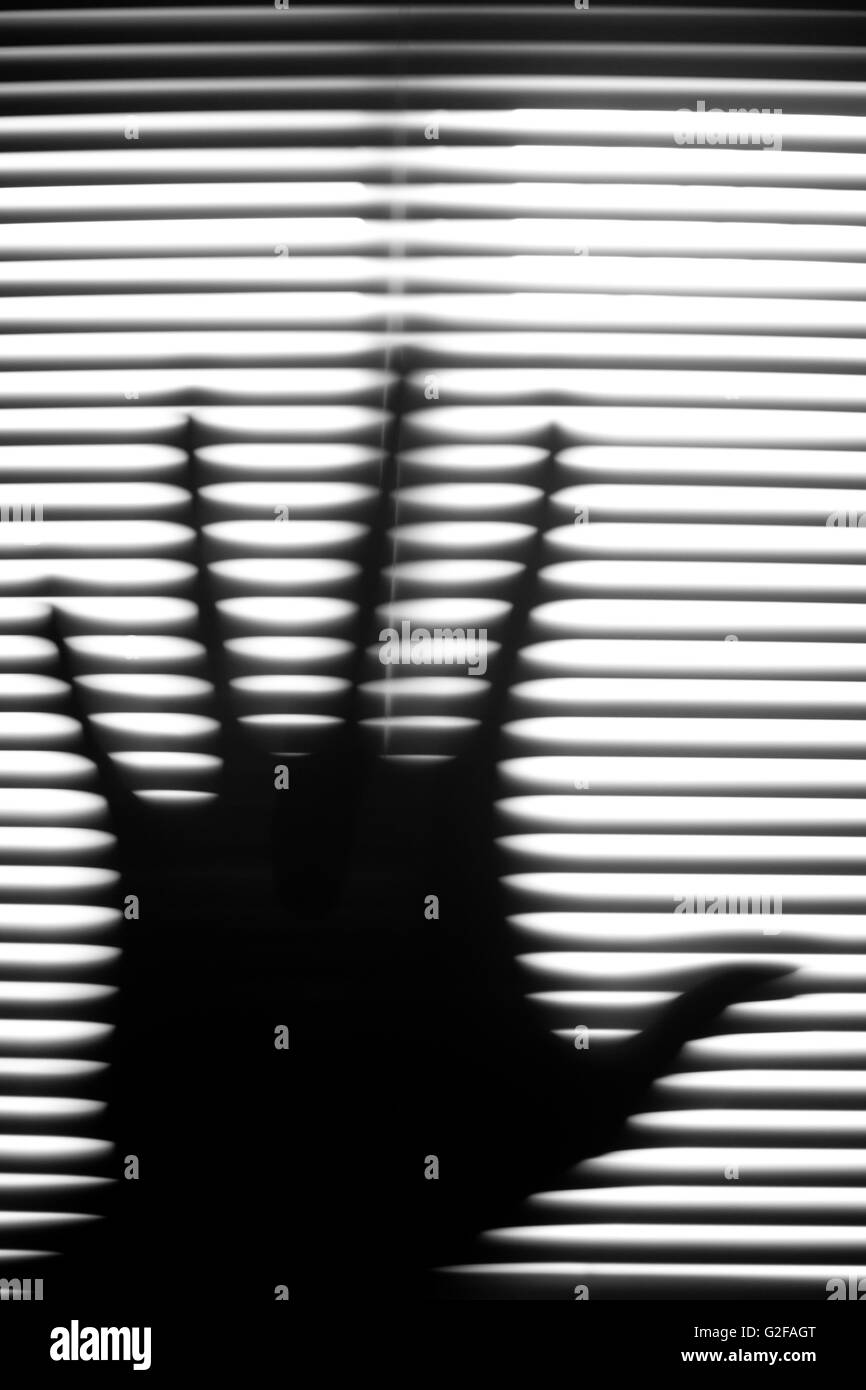 Hand-Silhouette gegen Jalousien, abstrakt Stockfoto