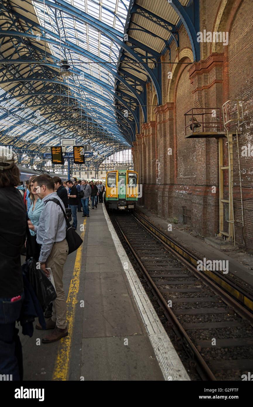 Passagiere warten auf einen Zug auf einer Plattform am Bahnhof von Brighton Stockfoto