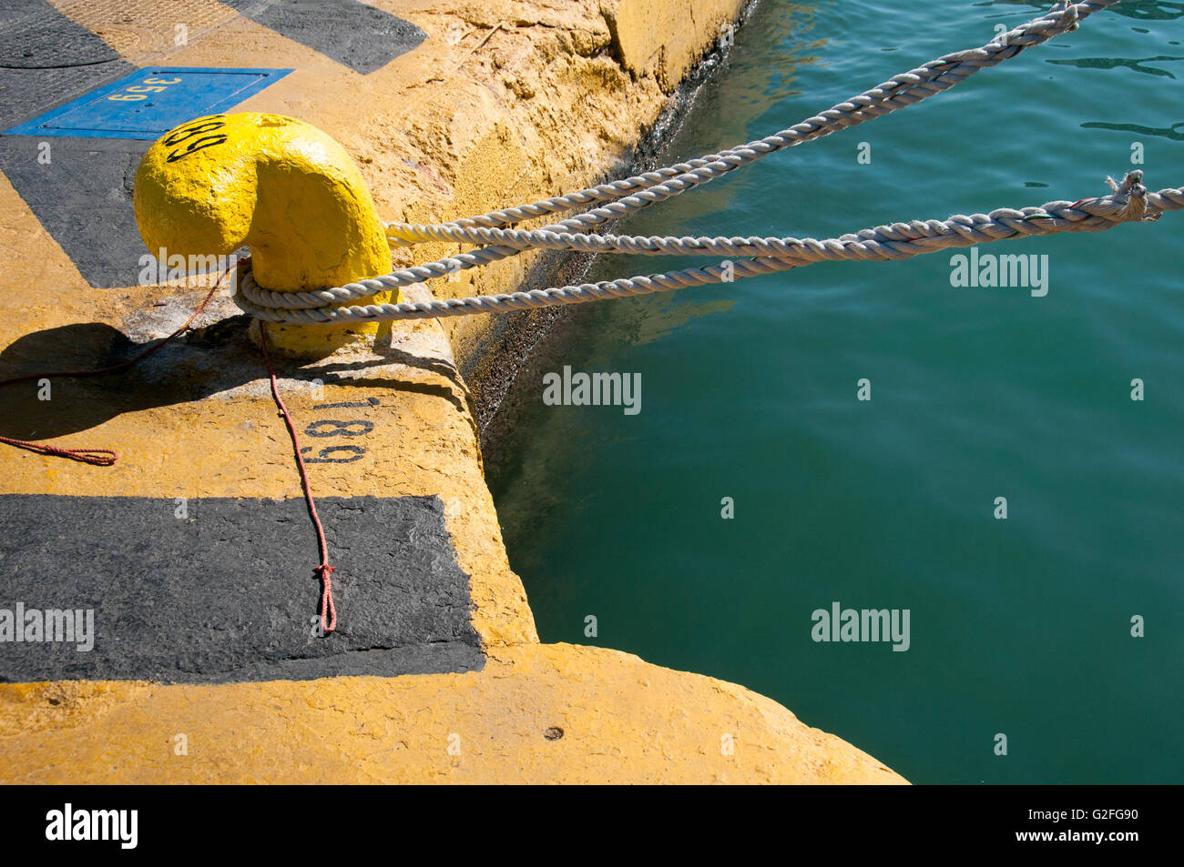 Gelbe konkrete Liegeplatz Klampe mit Seil gebunden um am Hafen von Piräus in Athen, Griechenland. Stockfoto